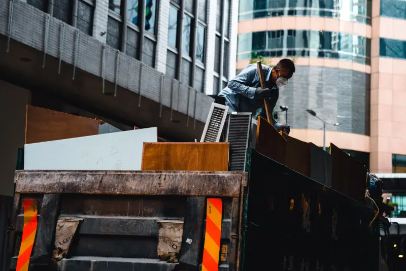 Worker loading construction debris into the back of a truck
